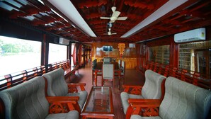 A train car with wooden paneling, a central table, and seating along the sides. - My Trip Houseboat (Kuttanad Taluk)