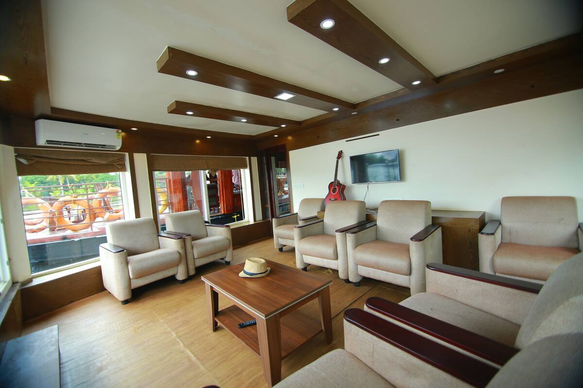 A spacious living area with multiple sofas and armchairs, a wooden coffee table, and a mounted television.