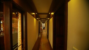 A long, narrow hallway with wooden floors and walls, leading to a door at the end. - My Trip Houseboat (Kuttanad Taluk)