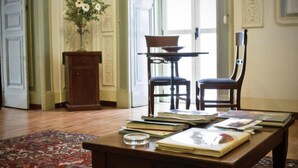 A room with a wooden table, books, a vase with flowers, and a chair. - Miseria e Nobiltà (Naples)