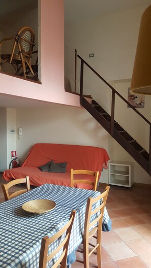 A cozy room with a bed, a dining table with chairs, and a staircase. - Miseria e Nobiltà (Naples)