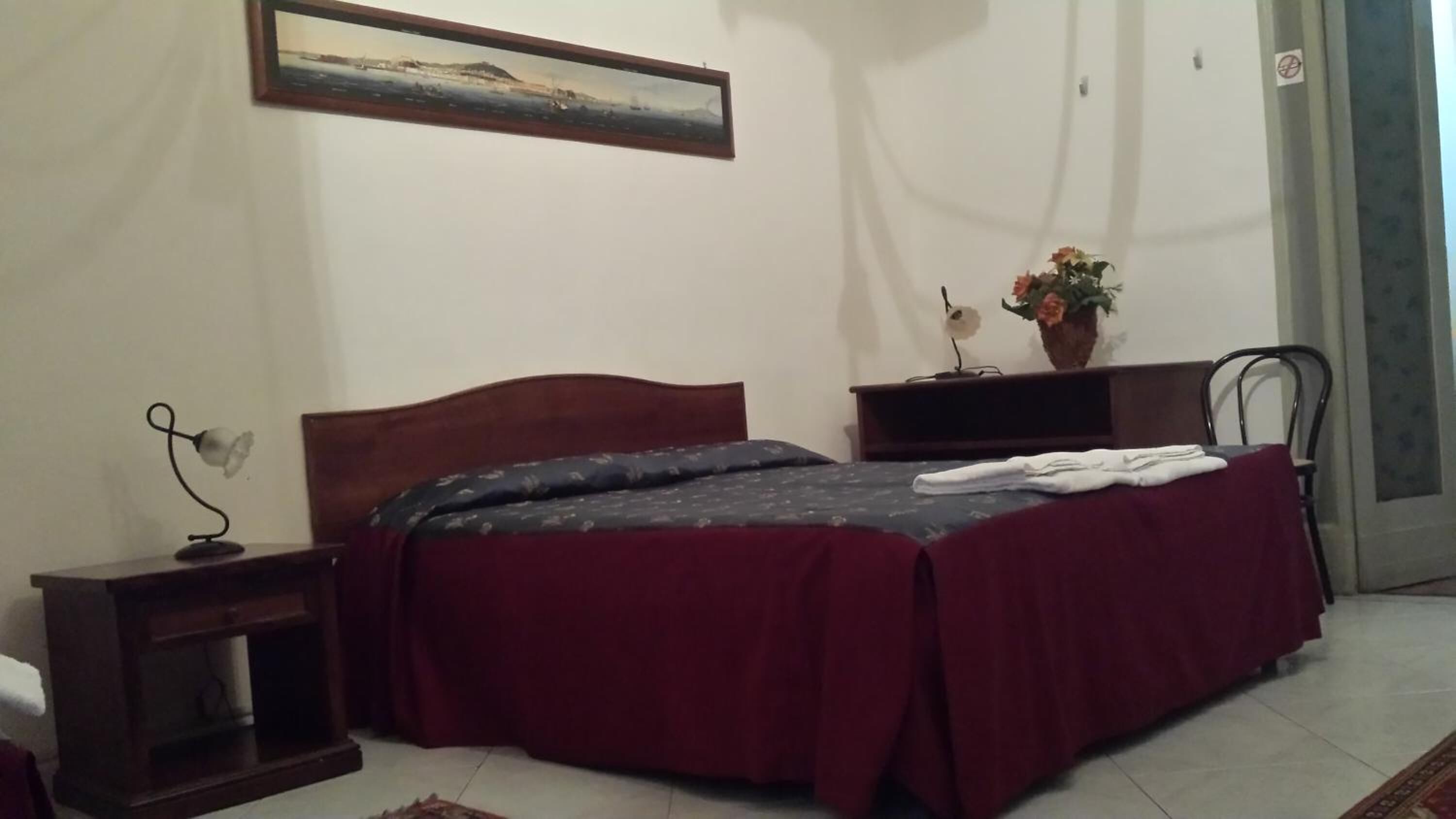 A bedroom with a bed, a nightstand, a dresser, a chair, and a painting on the wall.