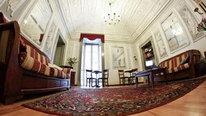 A room with ornate ceiling, a large patterned rug, and a sofa with striped cushions. - Miseria e Nobiltà (Naples)