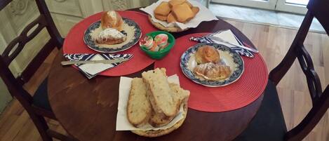 A dining table with plates of pastries, bread, and a small bowl of fruit.