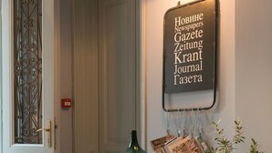 Een gang met een vintage koffer, een groene vaas en een bord met buitenlandse tekst.