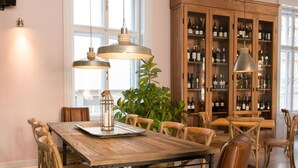 Een eetgedeelte met een houten tafel, lederen stoelen en een wijnkast.