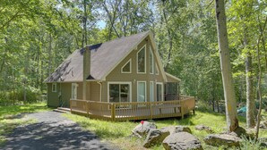 A cabin with a deck, surrounded by trees. - Pools, Hot Tub & More: Bushkill Mountain Getaway! (Bushkill)