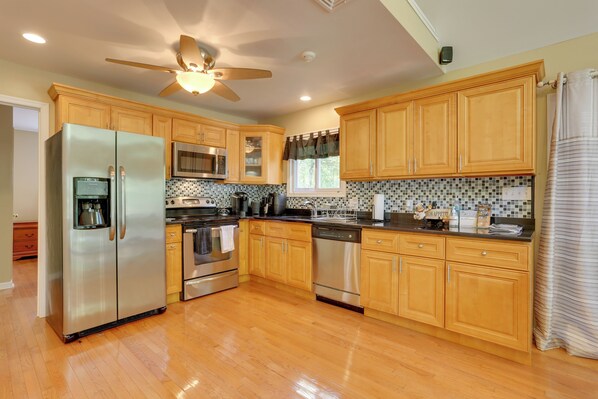 A modern kitchen with wooden cabinets, stainless steel appliances, and a tiled backsplash.