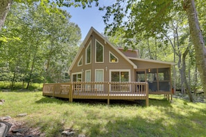 A cabin with a deck, surrounded by trees.