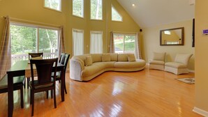 A spacious living room with a large L-shaped sectional sofa, a dining table with chairs, and a ceiling fan. - Pools, Hot Tub & More: Bushkill Mountain Getaway! (Bushkill)