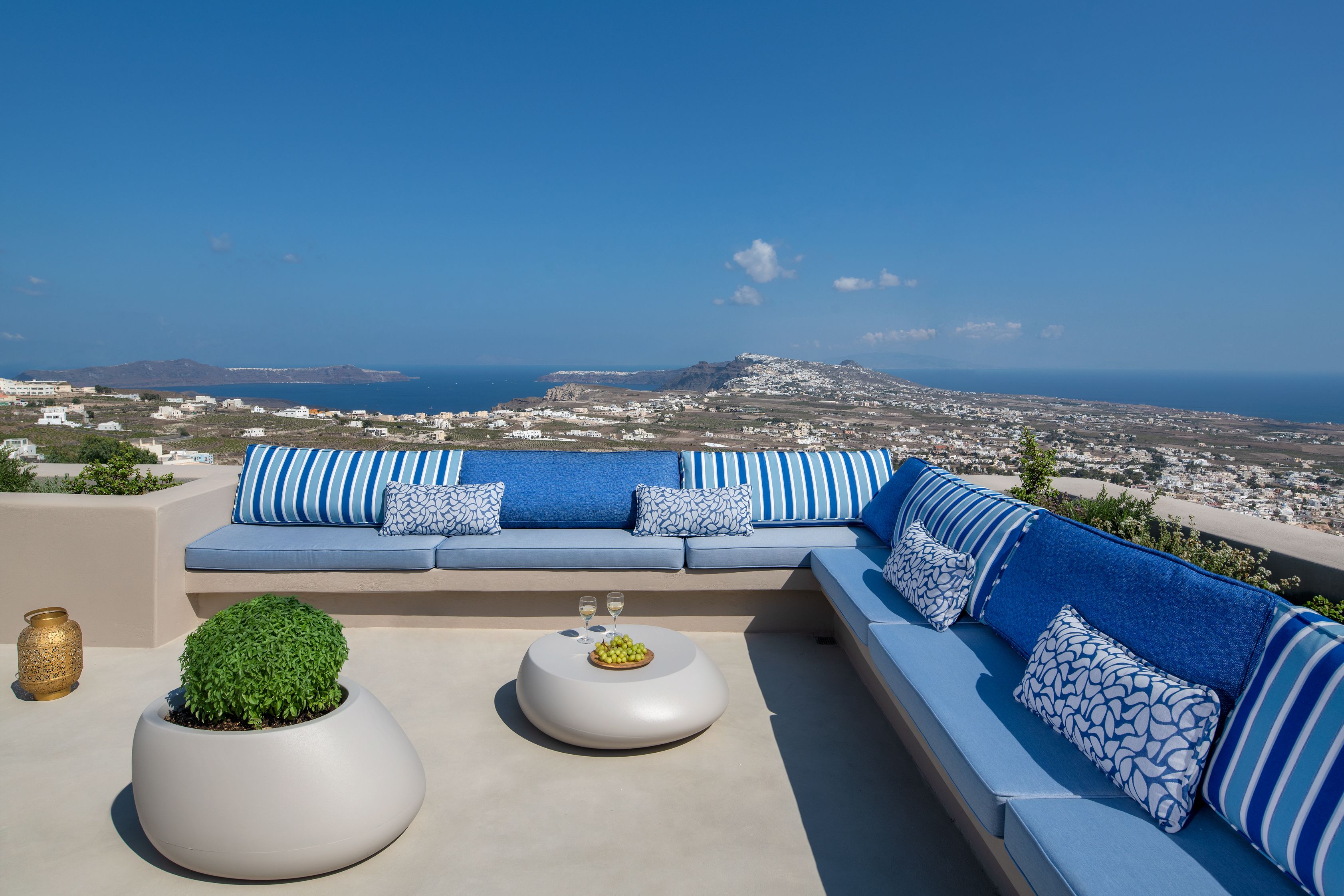 Una terraza en la azotea con un sofá a rayas azules, una mesita con un frutero y una planta en maceta.