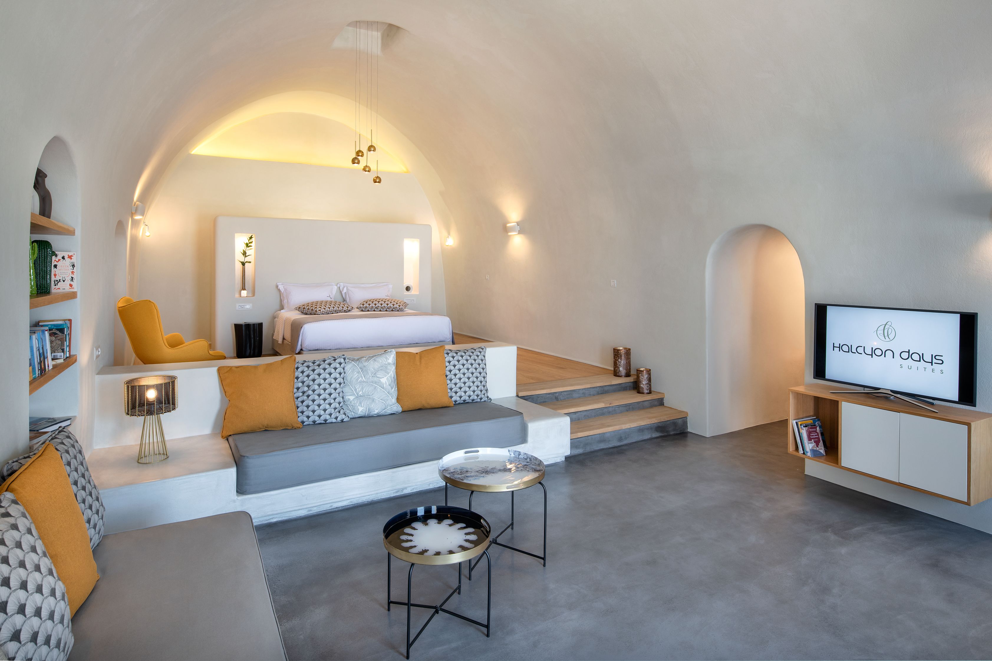 A modern hotel room with a bed, sofa, TV, and a small table.