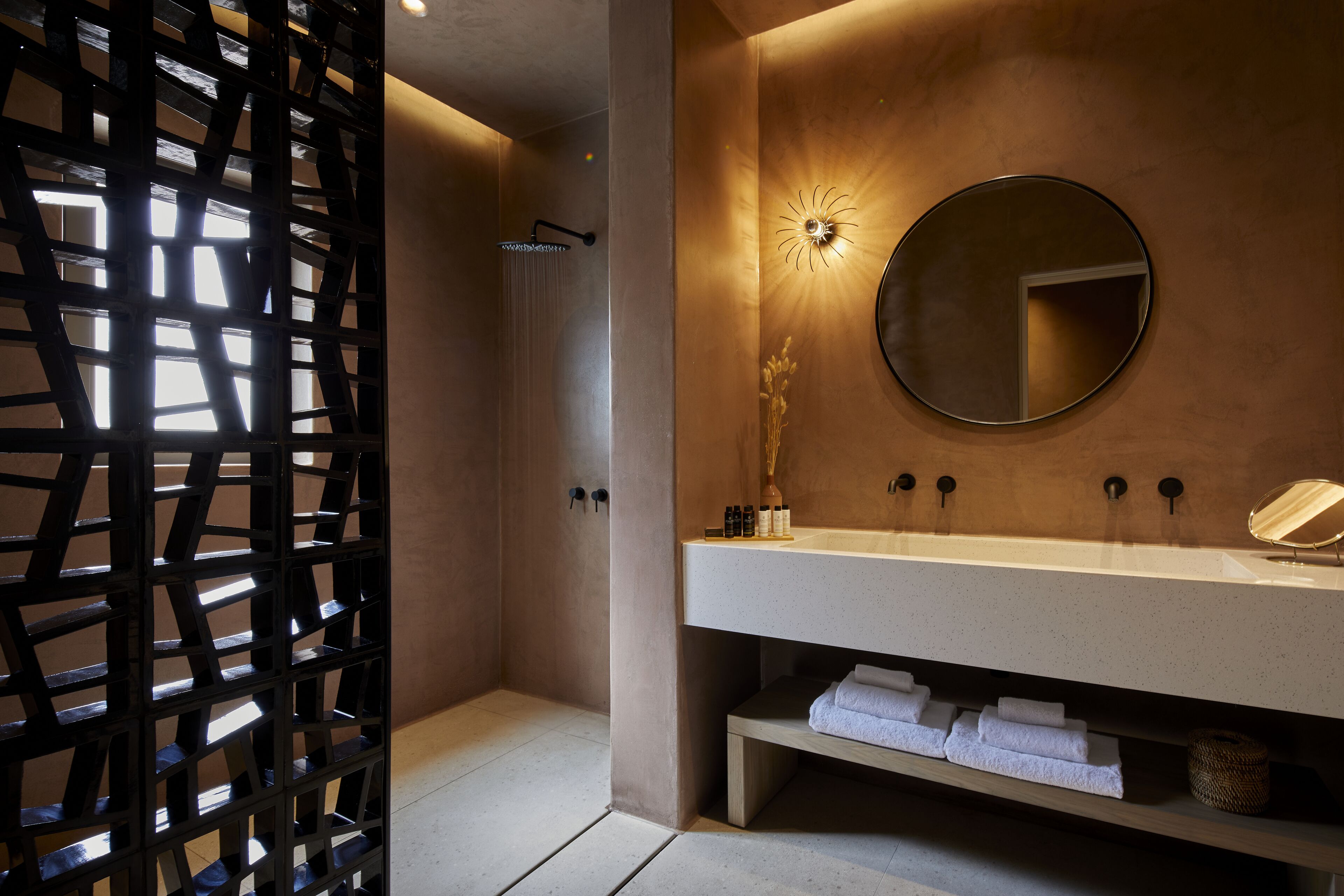 Un baño moderno con ducha, lavamanos con espejo y un perchero para toallas.