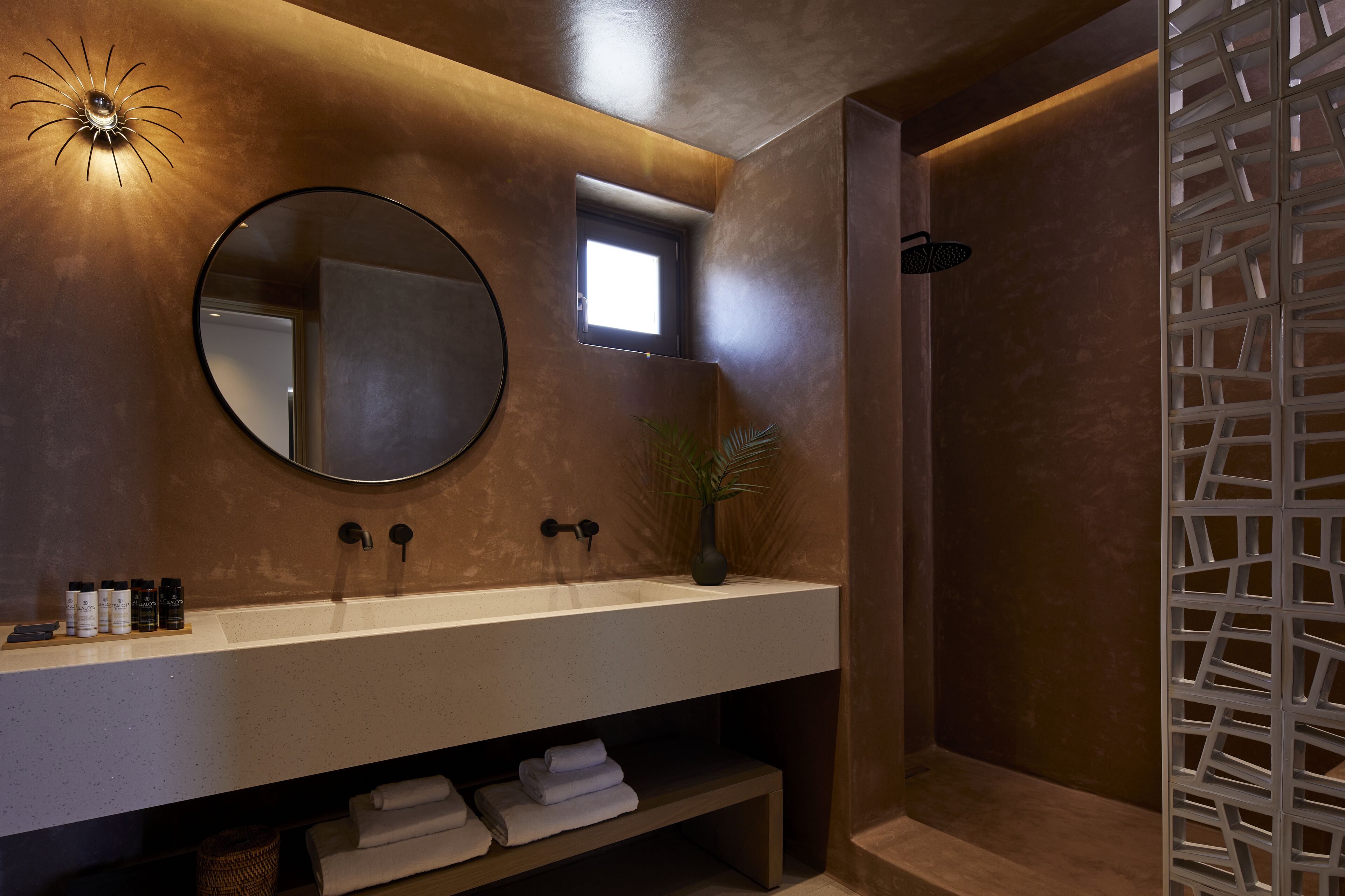 Un baño moderno con un espejo grande, un lavabo redondo y una zona de ducha.