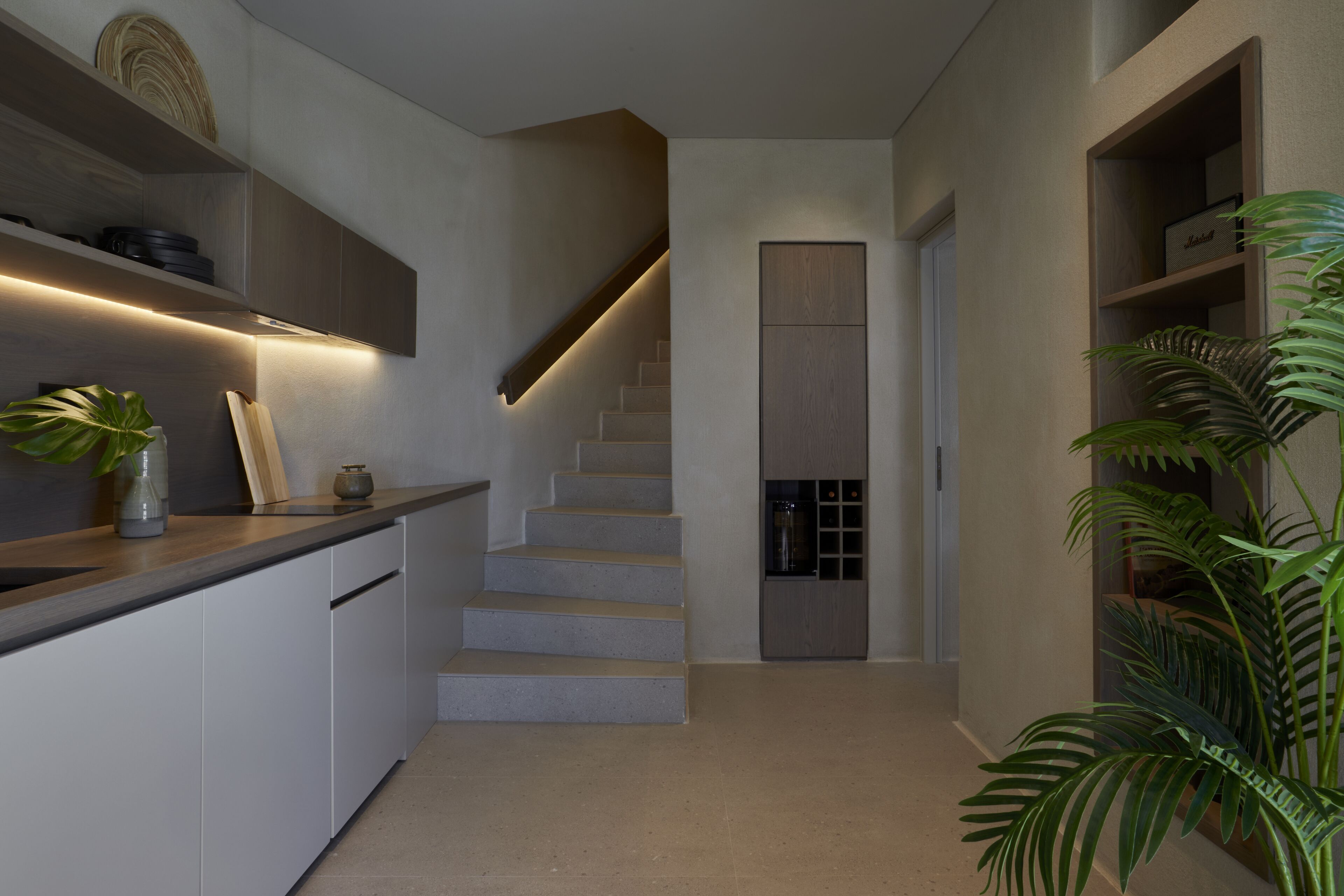 A modern kitchen with built-in cabinets, a countertop, and a staircase leading to a landing.