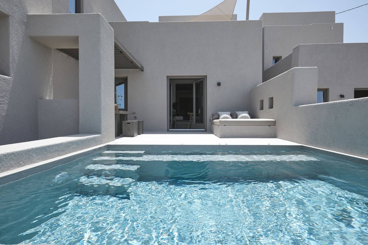 A swimming pool with a clear blue water surface, surrounded by a modern building with a minimalist architectural style.