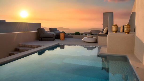 Piscina infinita en la azotea con vista al atardecer, sillas de descanso y jarrones decorativos.