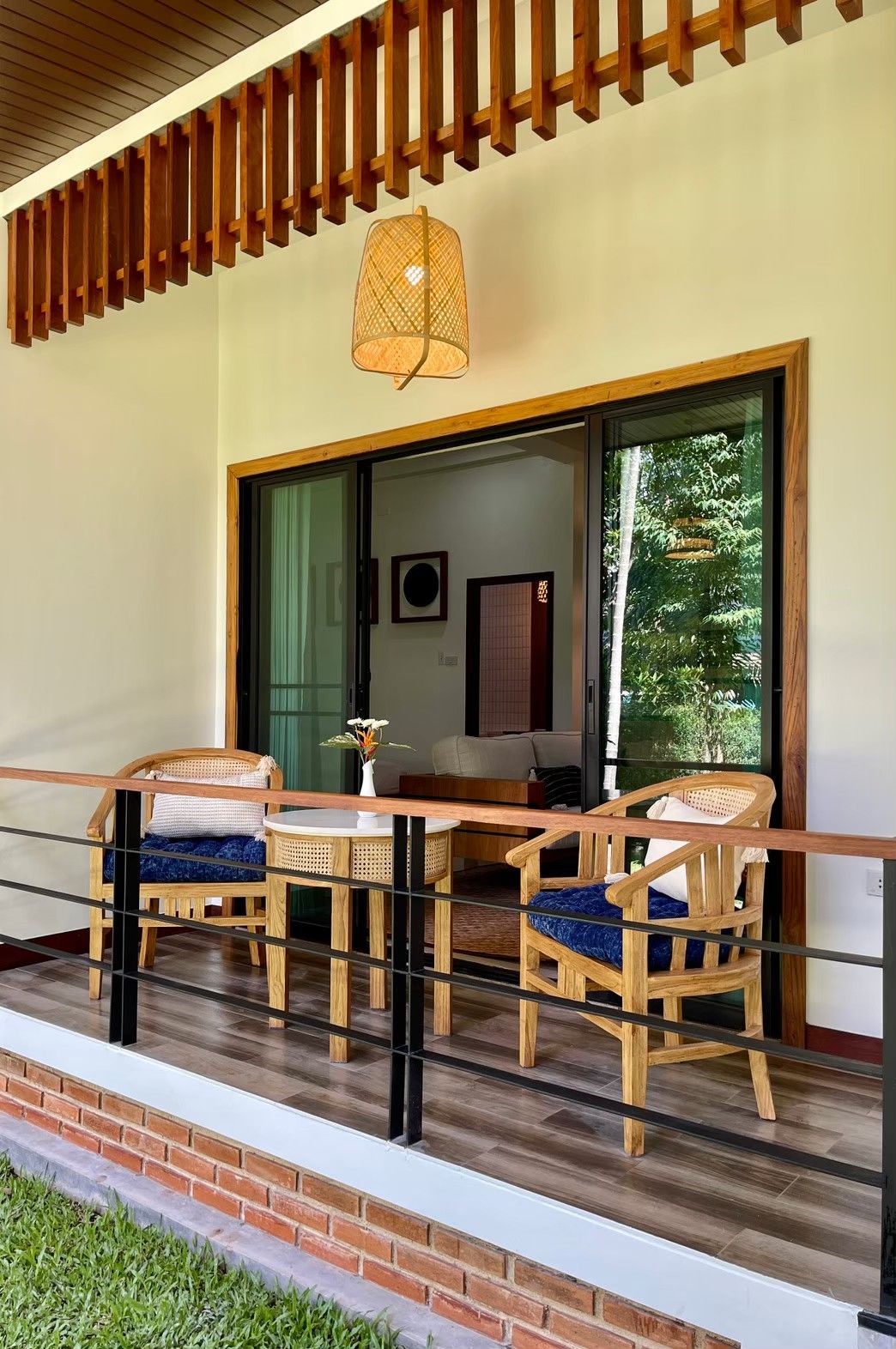 Un balcón con mobiliario de madera, una lámpara colgante y vistas al verdor exterior.