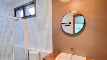 A bathroom with a toilet, a sink, and a shower area.