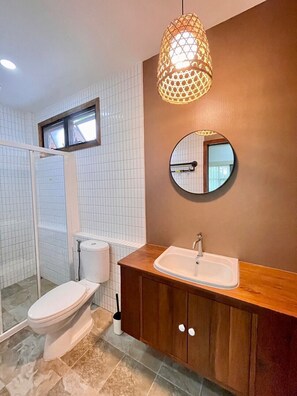 A bathroom with a toilet, a sink, and a shower area. - Tai resort (San Pa Thong)