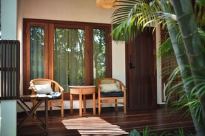 A room with two wicker chairs, a small table, and a wooden floor. - Tai resort (San Pa Thong)