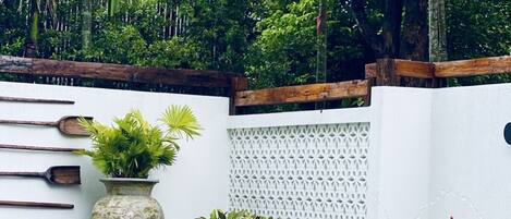 A pool surrounded by lush greenery and a white wall with a lattice design.