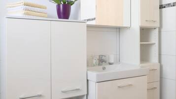 A modern bathroom with white cabinetry, a mirror, and a purple orchid.