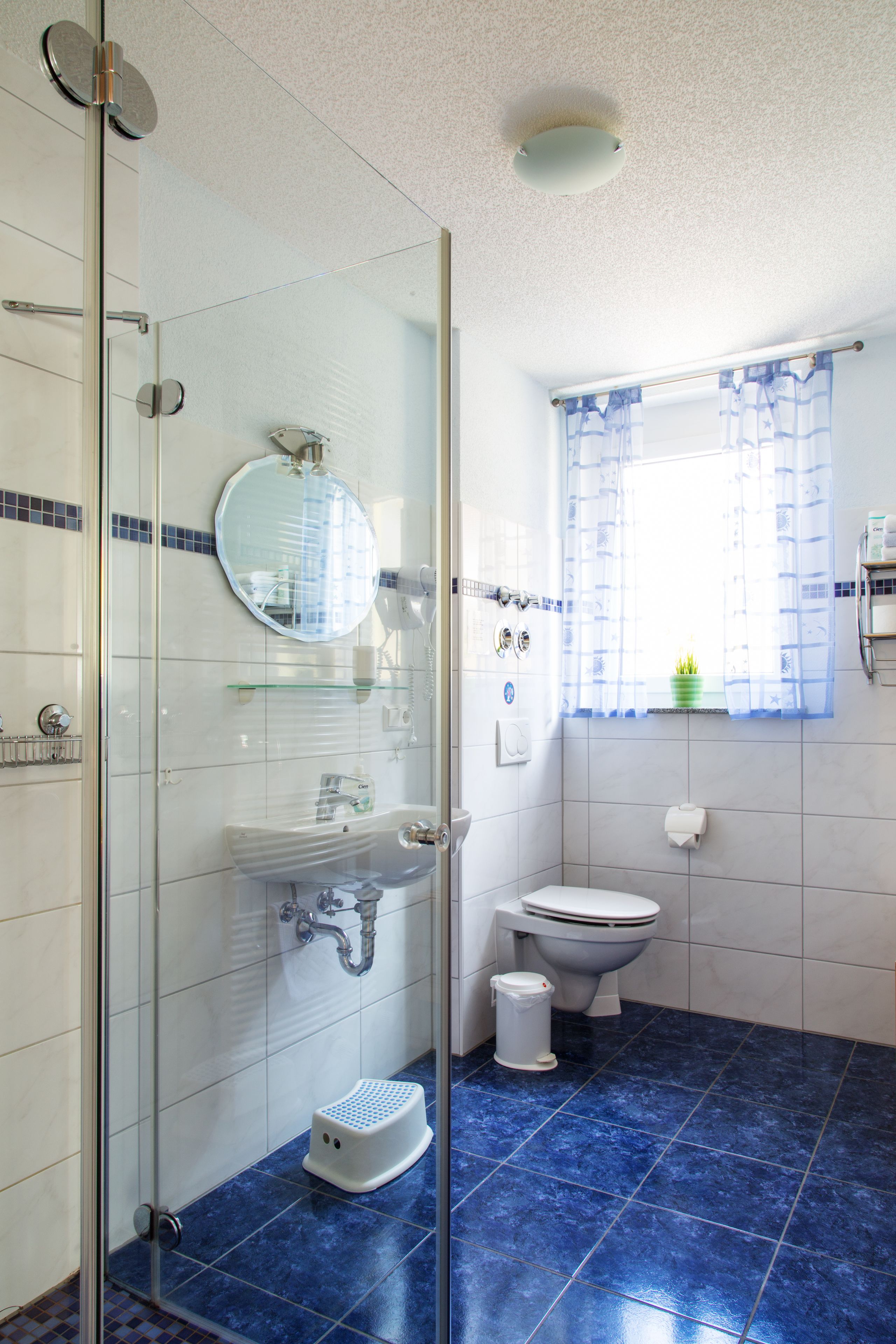 A bathroom with a glass shower enclosure, a toilet, and a sink with a mirror.