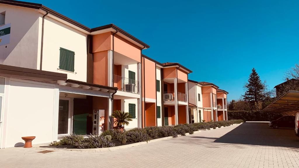A row of multi-story buildings with balconies, a paved driveway, and a clear sky.