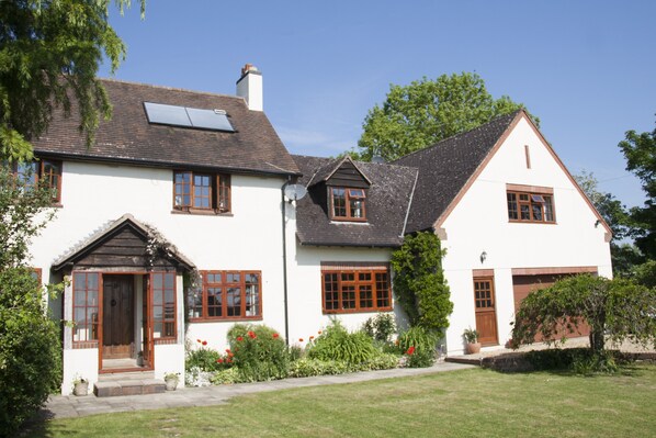 A two-story house with a white exterior, brown trim, and a sloped roof.