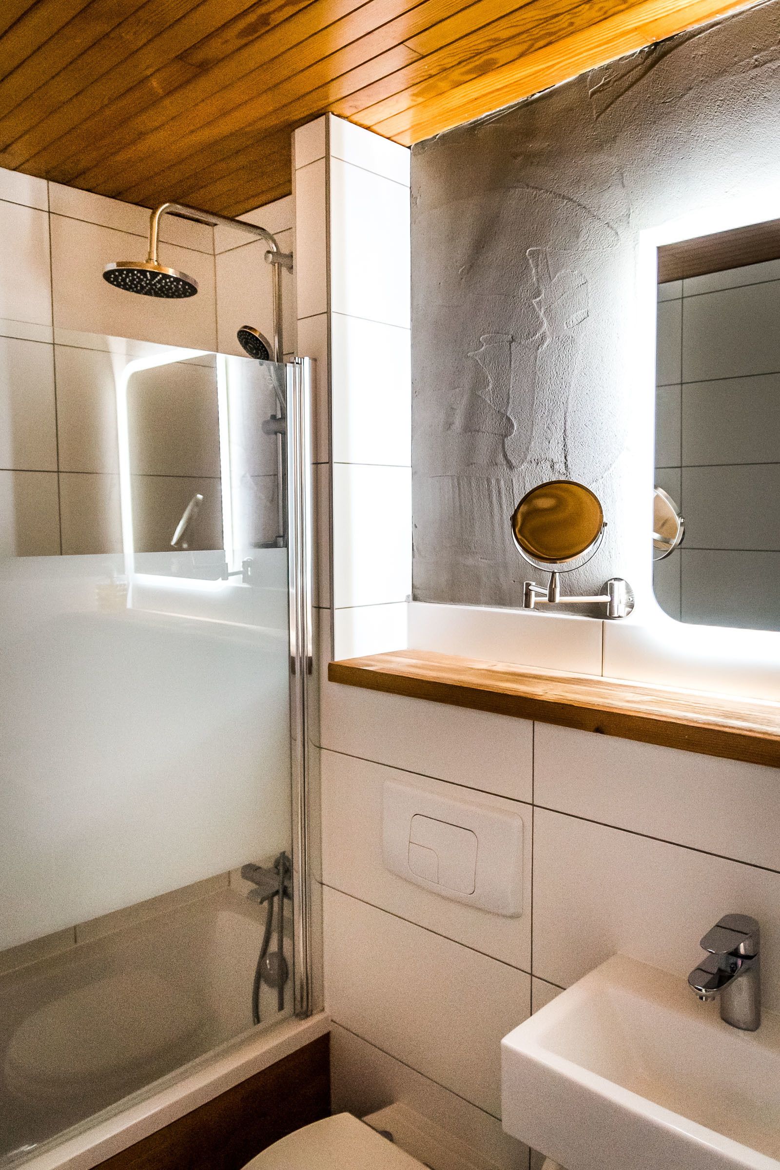 A modern bathroom with a glass-enclosed shower, a wooden vanity, and a large mirror.