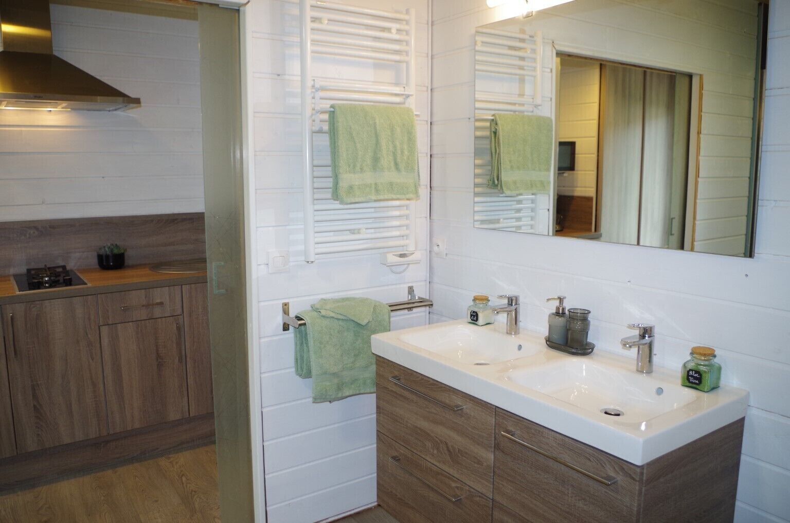 Un baño con lavamanos doble, armarios de madera, un espejo y un perchero para toallas.