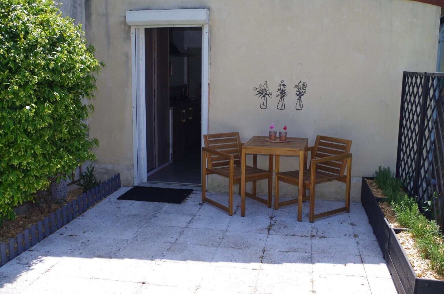 A patio with a wooden table and chairs, a door, and a wall-mounted decoration.