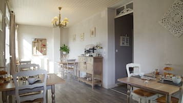 A dining area with wooden tables and chairs, a chandelier, and a wall-mounted decorative piece.