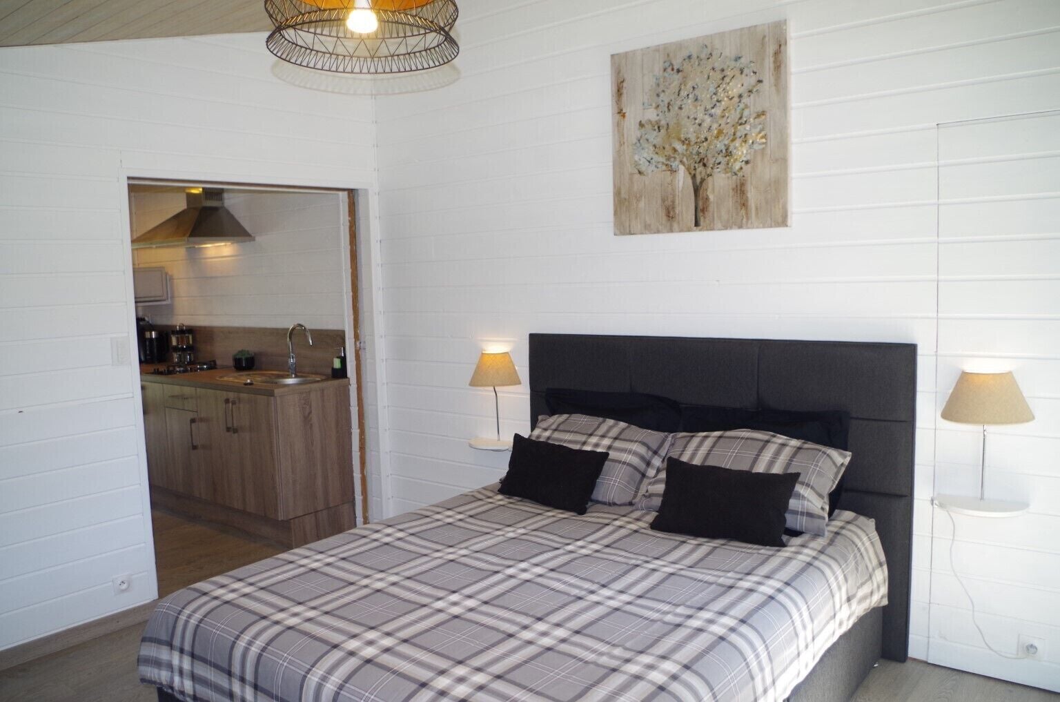 A bedroom with a bed, two bedside lamps, a headboard, and a painting on the wall.