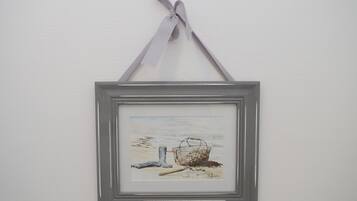 A framed artwork of a fishing net and boot on a beach.