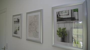 A wall with three framed artworks, a door, and a window with a plant.