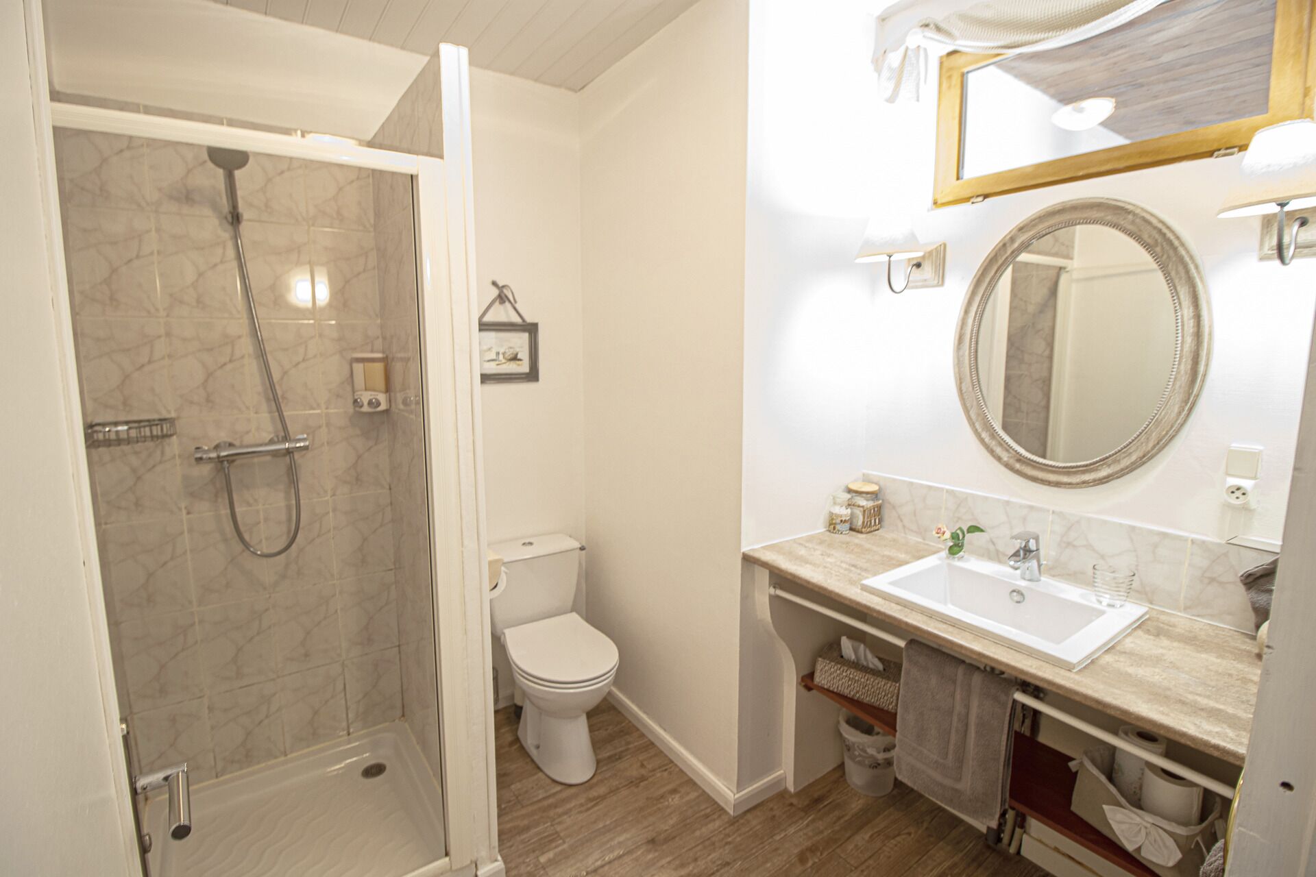 Une salle de bain avec une douche à parois de verre, des toilettes, un lavabo avec un miroir et un porte-serviettes.