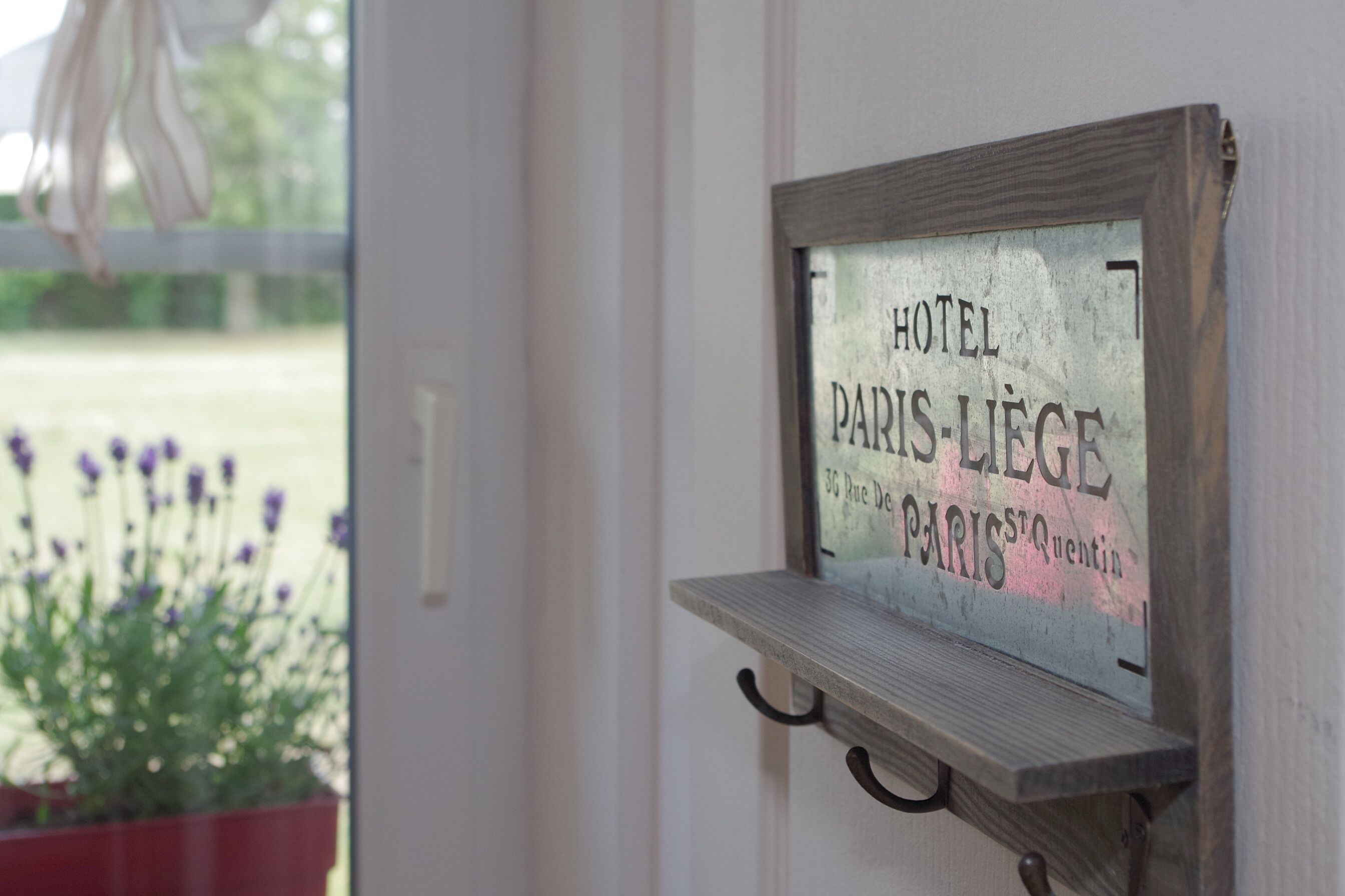 Um letreiro com o texto 'HOTEL PARIS-LIEGE' fixado em uma parede.