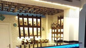 Una zona de bar con mostrador iluminado en azul, paneles decorativos en la pared y una puerta blanca.