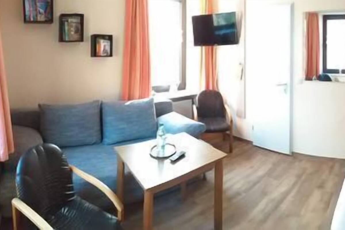 A hotel room with a bed, a sofa, a small table, and a TV.