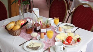 A breakfast setting with a variety of food items including bread, eggs, cheese, and fruits on a table with a white tablecloth. - Pension & Gasthaus Kattenstieg (Heiligengrabe)
