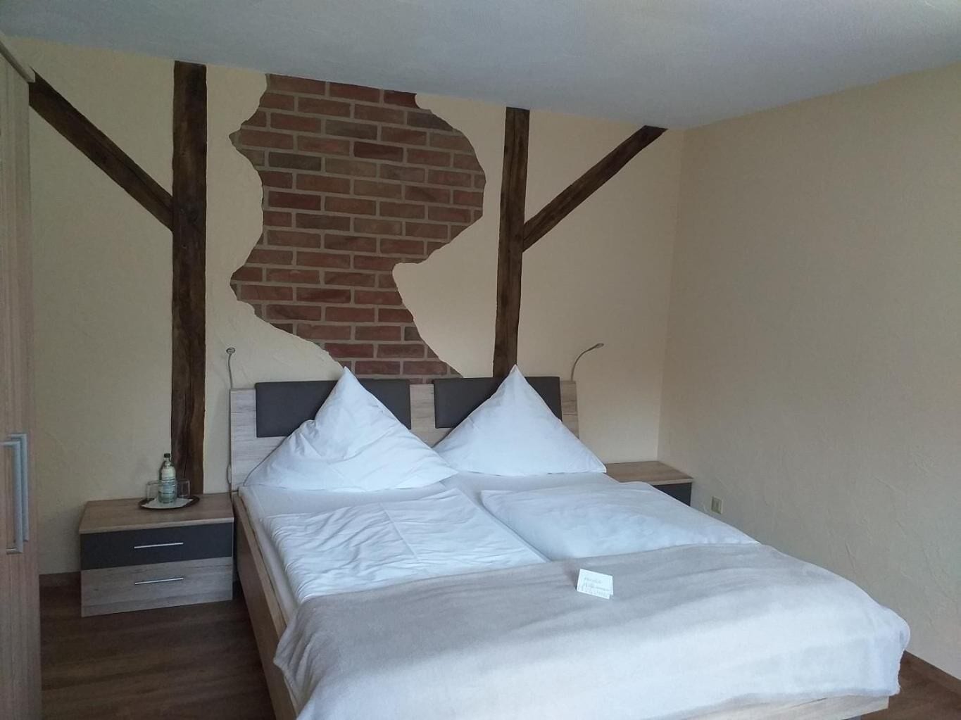 Ein Schlafzimmer mit Bett, zwei Nachttischen, einem Holzkopfstück und einer Ziegelwand.