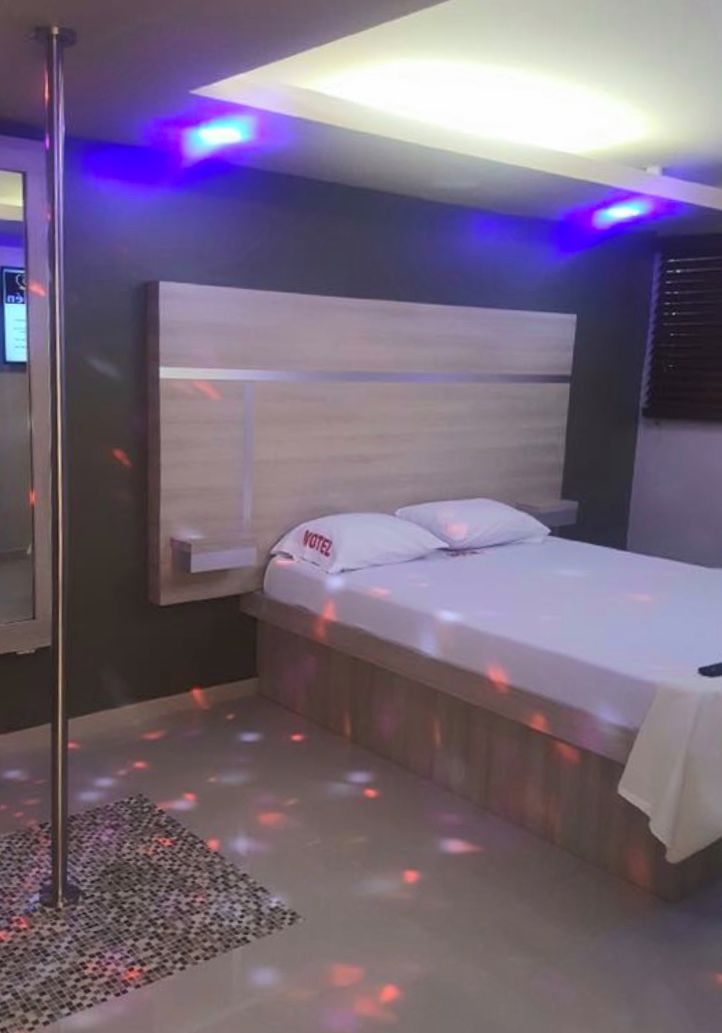 A single bed with a headboard, a bedside table, and a wall-mounted TV.