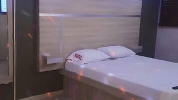 A single bed with a headboard, a bedside table, and a wall-mounted TV.