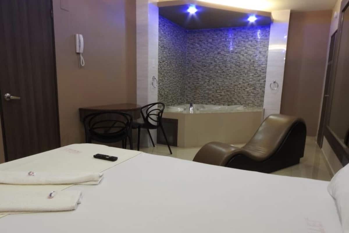 A hotel room with a bed, a desk, a chair, and a bathtub.