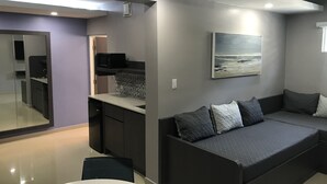 A modern living space with a kitchen area, a dining table, and a sofa with cushions. - Hotel Nuevo Mejico (Ponce)