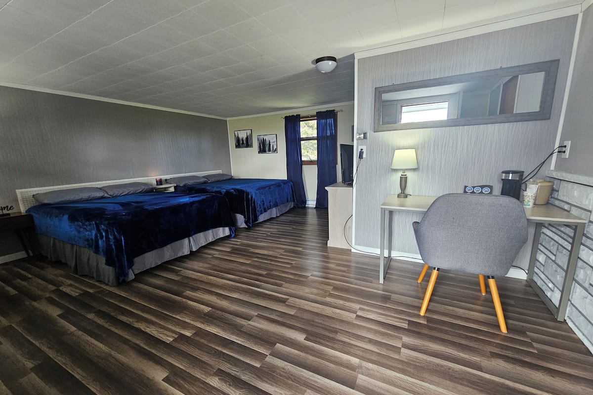A room with two beds, a desk, and a chair.