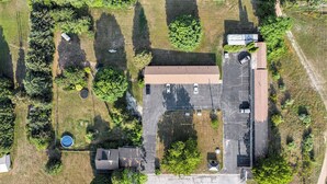An aerial view of a parking lot with a building, trees, and a small circular structure. - The Last Resort (Hart)