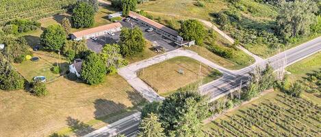 Vista aérea de una propiedad con un edificio grande, estacionamiento y campos circundantes.